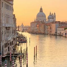 the sun is setting in venice, italy as boats are parked along the side of the water