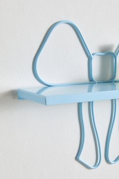 a blue shelf with a cat shaped object hanging on it's side next to a white wall