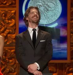 a man in a suit and tie standing next to a woman wearing a red dress