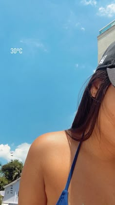 a woman wearing a hat and eating a donut in front of a blue sky