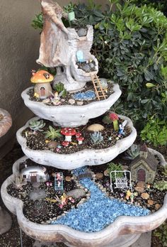 three tiered garden planter with gnome figurines on top and plants in the bottom