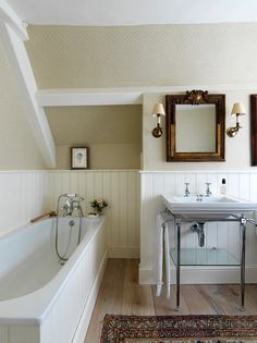 a bath room with a sink a mirror and a bath tub under a skylight