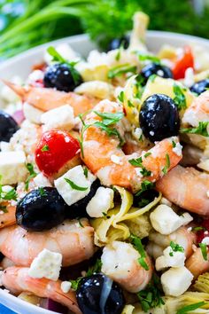 a salad with shrimp, olives, fettuccine and blueberries in a white bowl