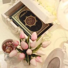 a person holding a flower in front of an open book with arabic writing on it