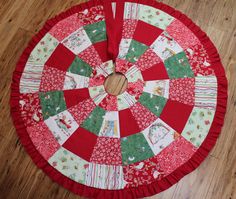 a red and green quilted table top with a wooden circle in the center on a wood floor