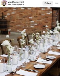 the table is set with white flowers and place settings for dinner guests to sit at