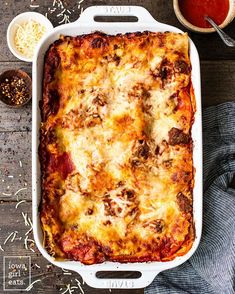 a casserole dish with meat, cheese and sauce on the side next to two bowls