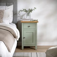 a small green nightstand next to a bed