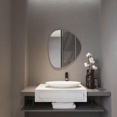 a bathroom with a sink, mirror and vase on the counter in front of it