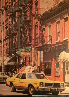 an old yellow car is parked on the street in front of some buildings and fire escapes