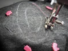 the sewing machine is being sewn with pink thread and needles on top of it