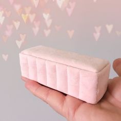 a hand holding a small pink box with hearts on it