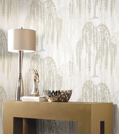 a table with a lamp, bowl and vase on it in front of a wallpapered background