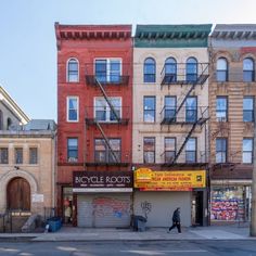 a row of buildings on the corner of a street in front of a man walking by