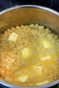 macaroni and cheese being cooked in a pot on the stove