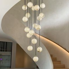 an elegant chandelier hanging from the ceiling in a modern house with spiral staircase