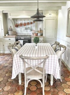 a kitchen with a table and chairs in the middle of it, surrounded by white cabinets