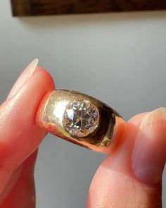 a close up of a person holding a gold ring with a diamond in the middle