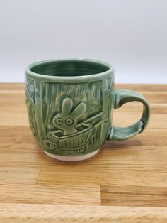 a green coffee cup sitting on top of a wooden table