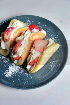 two crepes with strawberries and whip cream on them sitting on a plate