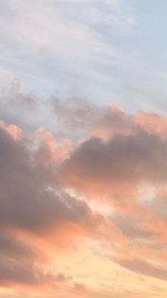 the airplane is flying high in the sky at sunset or dawn, with some clouds behind it