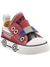 a pair of red and white shoes with cars on the bottom, one shoe has an eye patch