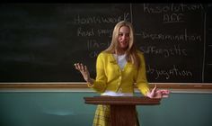 a woman standing at a podium in front of a chalkboard