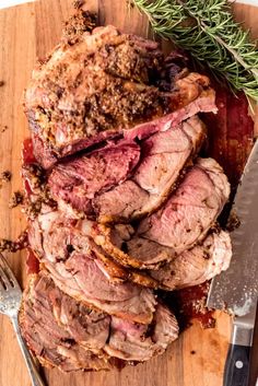 sliced roast beef on cutting board with knife and rosemary sprig