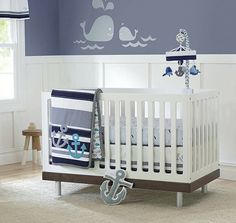 a baby's room decorated in blue and white with whale decals on the wall