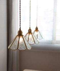 three lights hanging from a ceiling in front of a window