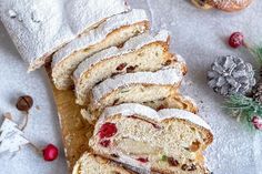 a loaf of cranberry bread with powdered sugar on top and pine cones next to it