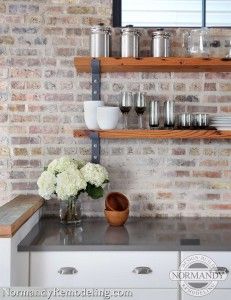 a kitchen counter topped with lots of pots and pans next to a brick wall