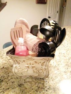 kitchen utensils and cleaning supplies in a ceramic dish on a granite countertop