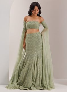 Step into elegance with the Mint Green Mermaid Jaal Lehenga, a striking fusion of sophistication and glamour. Crafted from luxurious organza and shimmer chiffon,, this stunning mint green lehenga showcases intricate crystal and cut dana embroidery in a captivating snowflake jaal design. The soft, flowing lehenga is enhanced by the mermaid cut, which flatters the figure while maintaining an ethereal grace. Paired with an off-shoulder blouse featuring dramatic, floor-length sleeve. Standout lehenga choice for Mehndi, Sangeet, or as wedding guest attire. Composition : Lehenga, Blouse - Organza, Shimmer Chiffon, and Chantoon Care: Dry Clean Only and Vacuum Storage This product can be customized for sleeves, blouse length and neckline Delivery : 6-8 weeks as the product is hand crafted. Check S Mermaid Cut Lehenga, Cut Dana Work Embroidery, Lengha Simple, Udaipur Outfits, Mermaid Lehenga, Indian Engagement Outfit, Mint Green Lehenga, Off Shoulder Lehenga, Blouse Organza