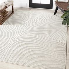 a white rug with wavy lines on it in front of a black door and window