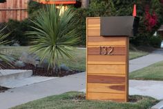 a mailbox sitting on the side of a sidewalk next to a tree and grass