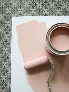 a pink paint can and roller on top of a white table