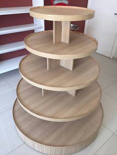 three tiered wooden shelf in the middle of a room with white tile flooring