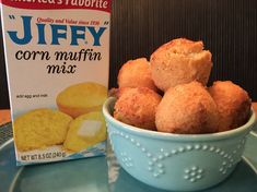 a blue bowl filled with corn muffins next to a carton of jelly