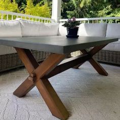 a wooden table sitting on top of a white floor next to a couch and potted plant