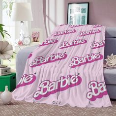 a pink blanket with barbie's name on it in the middle of a living room