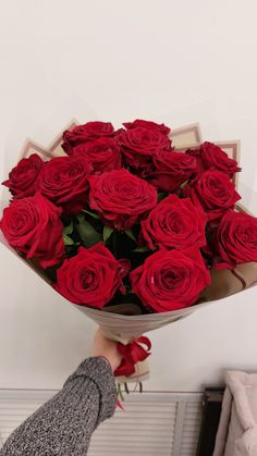 a person holding a bouquet of red roses