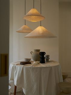 a table with three lamps hanging from it's ceiling and plates on the table