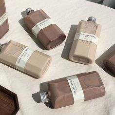 five different types of soaps sitting on a white tablecloth with labels in front of them