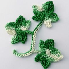 two crocheted shamrocks on a white surface