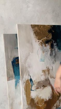 a person is painting on the wall with blue and brown colors