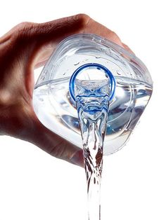 a hand holding a clear glass object in it's right hand with water pouring out of it