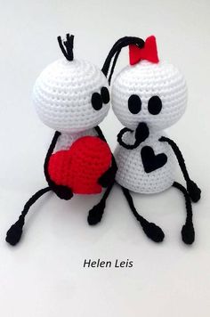 two crocheted white and black bugs holding a red heart