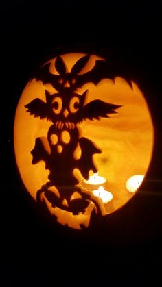 a pumpkin carved into the shape of a dragon in front of a full moon with candles