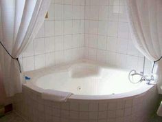 a white bath tub sitting in a bathroom next to a toilet and shower curtained window